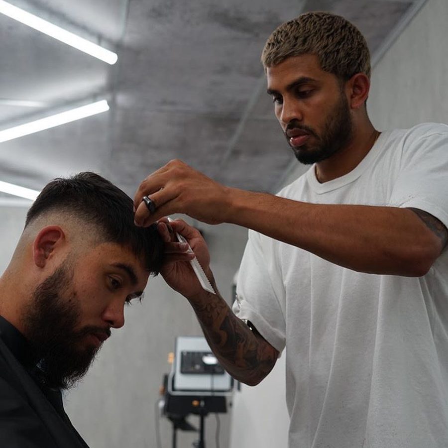 A barber cutting a client's hair with scissors and comb.
